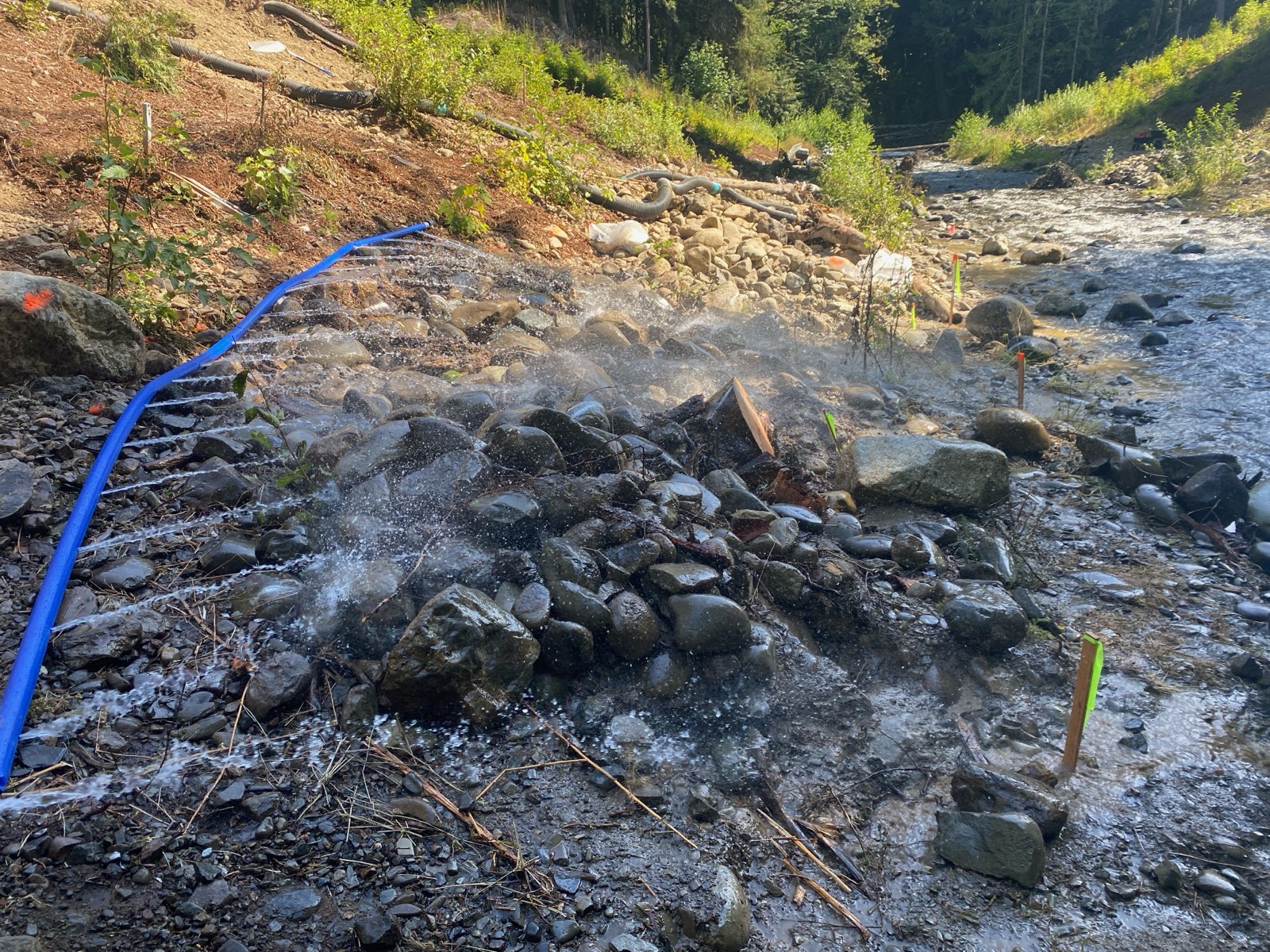 A water flushing unit sprays creek rocks in Indian Creek as a part of cleanup operations.